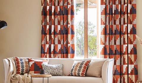 Harlequin Mirador orange and navy blue fabric curtains and cushions in lounge